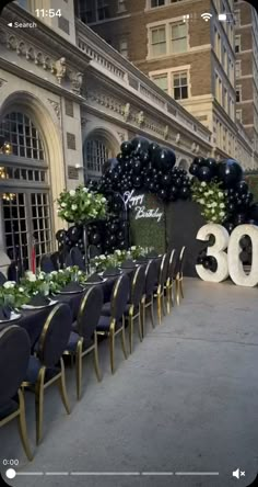 tables and chairs are set up in front of a large number sign with balloons on it