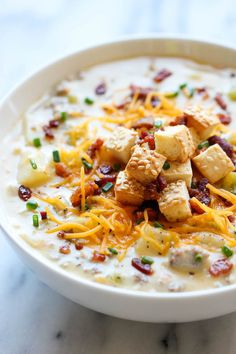 a white bowl filled with soup topped with tofu and cheese