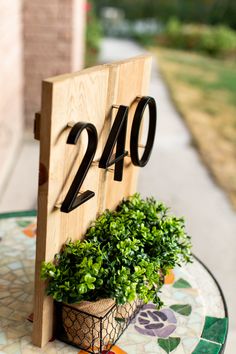 a house number sign sitting on top of a table next to a potted plant