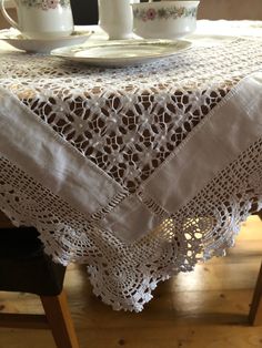 a table with two cups and saucers on it, next to a lace doily