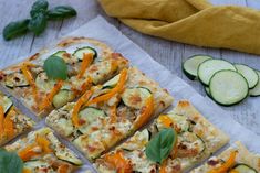 several slices of pizza with cheese and vegetables on paper next to sliced cucumbers