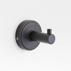 a black wall mounted toilet paper dispenser on a white wall with the lid down