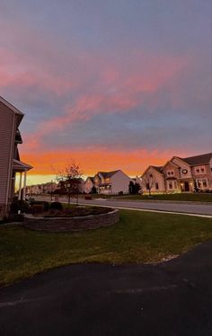 the sun is setting over some houses and lawns in an area with green grass