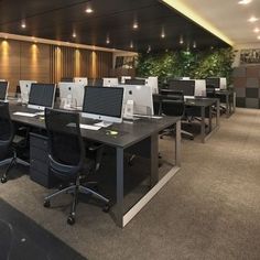 an office with rows of desks and computers on the tables in front of them