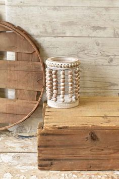 a white vase sitting on top of a wooden box next to a round wall mirror