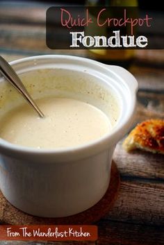 a white bowl filled with soup sitting on top of a wooden table next to bread