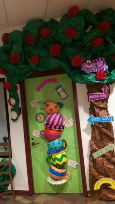 this is a door decorated to look like a tree with flowers on it and a teddy bear wearing a hat