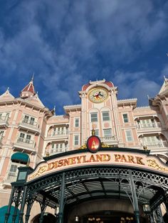 the front entrance to disneyland land park with a clock on it's face and sky in the background