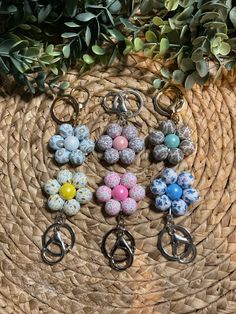 six keychains with different designs on them sitting on a woven basket next to some plants