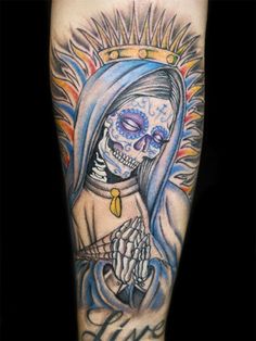 a person with a skull on their arm holding a cross and wearing a blue robe