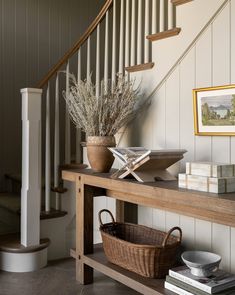 a wooden table topped with a basket next to a stair case