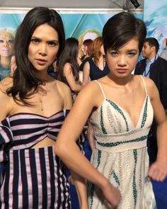 two women standing next to each other on a blue carpet