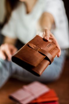 a woman is sitting on the floor with her wallet in hand and holding it open