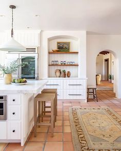 a large kitchen with white cabinets and counter tops, along with an area rug on the floor