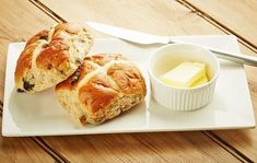 two hot cross buns on a white plate with butter