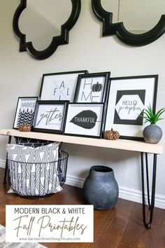 some black and white pictures hanging on a wall next to a table with vases