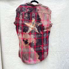 a red and black plaid shirt with a star on the back hanging from a hook