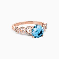 an oval blue topaz ring with diamonds on the band and side stones in rose gold