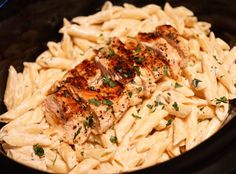 chicken and pasta in a crock pot with parsley on top, ready to be eaten