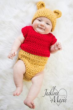 a baby wearing a winnie the pooh outfit laying on top of a white blanket