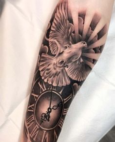 a clock and bird tattoo on the arm