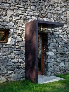 a building made out of rocks with a door and window on the outside, in front of it