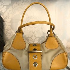 Fun Prada Tan Canvas And Leather Satchel Style Hobo. The Bag Has Two Top Handles And A Top Buckle Closure. There Is One Interior Zip Pocket. The Bag Is 14" In Length, 4.5" In Width, And 5" In Height. The Strap Drop Is 11". There Is Some Minimal Wear On The Bottom Of The Bag As Well As Near The Buckle Closure And Two Small Ink Stains On The Inside Lining. This Is A Great Everyday Bag. Designer Hobo Bag With Detachable Strap For Errands, Yellow Leather Shoulder Bag With Branded Hardware, Designer Satchel Hobo Bag, Designer Hobo Bag With Leather Handles, Designer Shoulder Bag With Gold-tone Hardware For Errands, Designer Beige Hobo Bag With Gold-tone Hardware, Yellow Bags With Silver-tone Hardware For Everyday Use, Yellow Rectangular Bag With Silver-tone Hardware, Designer Shoulder Bag With Leather Handles In Yellow