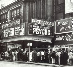 an old black and white photo of people standing in front of a movie theater on the corner