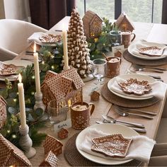 a table set for christmas with gingerbread houses and candles