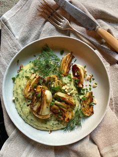 a white plate topped with mashed potatoes covered in sauce and garnished with herbs