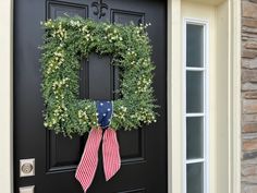 a wreath is hung on the front door of a house with an american flag bow