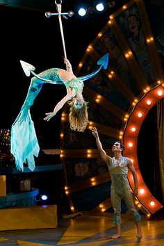 a man and woman performing on stage with lights in the background