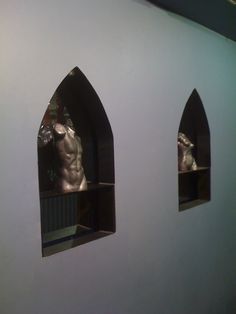 there are three windows in the wall that have statues on them and one is looking out