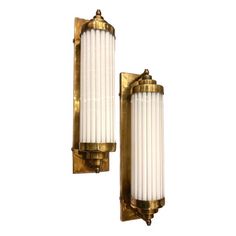 two brass sconces with white candles on them