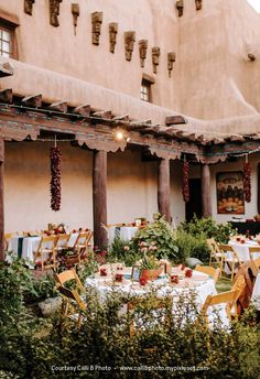 an outdoor dining area with tables and chairs set up in front of a building, surrounded by greenery