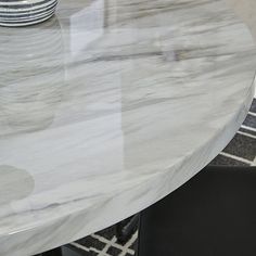 a white marble table with black chairs and a vase on the top, in front of it