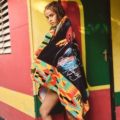 a woman leaning on the side of a train while wearing a colorful blanket over her head