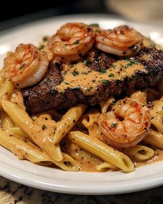 a white plate topped with pasta and meat covered in sauce next to shrimp on top of it