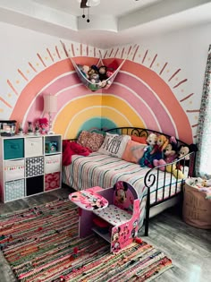 a child's bedroom decorated in pink, orange, and yellow with a rainbow theme