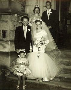 an old black and white photo of a bride and groom with their two children on the steps