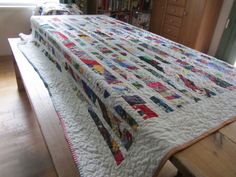 a bed with a quilt on top of it in a room next to a window