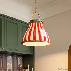 a red, white and blue lamp hanging from a ceiling in a kitchen with green cabinets