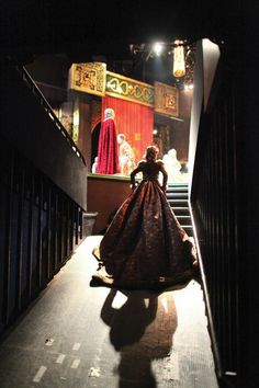 a woman in a gown is walking down the stairs to an auditorium with other people