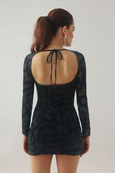 the back of a woman's body wearing a black dress with an open neck and long sleeves