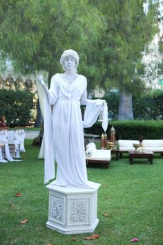 a white statue in the middle of a lawn