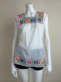 a mannequin wearing a white top with colorful flowers on the front and sides