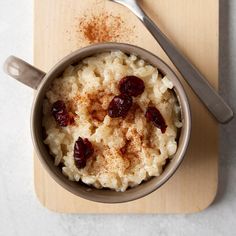 a cup filled with rice and raisins on top of a wooden cutting board