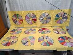 a table with several pieces of quilted material on it, including flowers and circles