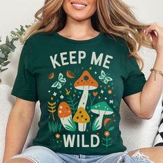 Retro Mushroom Shirt for Women Oversized Tshirt Nature Lover Gift Shirt for Her T Shirt Forest T-Shirt Boho Graphic Tee Women Keep Me Wild Embrace the outdoors with this boho mushroom shirt, a retro graphic tee that's perfect as an oversized nature lover gift for your free spirited friend or family member encouraging them to stay wild!  🍍𝗣𝗥𝗢𝗗𝗨𝗖𝗧 𝗜𝗡𝗙𝗢𝗥𝗠𝗔𝗧𝗜𝗢𝗡: * Exact Measurement Info in Listing Photos * Bella Canvas Unisex Short Sleeve Tee * Runs True to Size * Super Soft * 6 Sizes: S-3XL * Available in Asphalt, Autumn, Black, Forest Green, Maroon, Olive, Team Navy & Team Purple.  * Price is Same for All Sizes & Colors 🍍𝗖𝗔𝗥𝗘 𝗜𝗡𝗦𝗧𝗥𝗨𝗖𝗧𝗜𝗢𝗡𝗦: Wash Inside Out in Cold Water. No Bleach. Don't Dry Clean. Do Not Iron Directly on the Design 🍍𝗛𝗢𝗪 𝗧𝗢 𝗢𝗥𝗗𝗘𝗥 Green Trendy Top With Graphic Print, Trendy Green Tops With Text Print, Trendy Green Top With Text Print, Trendy Green Slogan T-shirt, Funny Crew Neck Tops With Letter Print, Green Crew Neck Top With Text Print, Trendy Green T-shirt With Slogan, Trendy Green T-shirt For Fall, Trendy Green Printed T-shirt