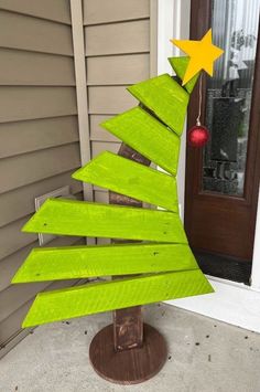 a christmas tree made out of wooden planks sitting in front of a home door